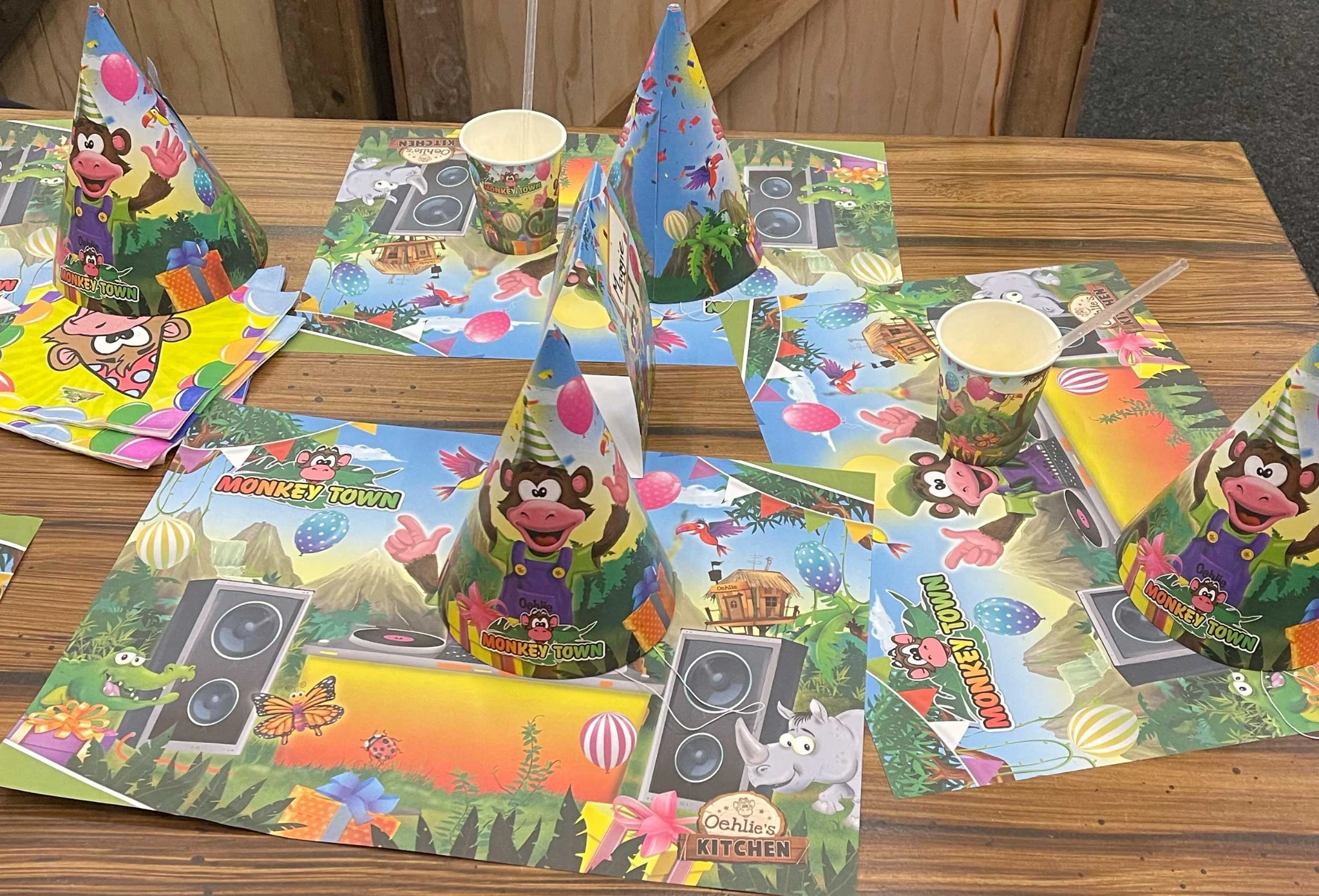 Feesttafel met bekers, feesthoedjes en placemats in de Monkey Town stijl