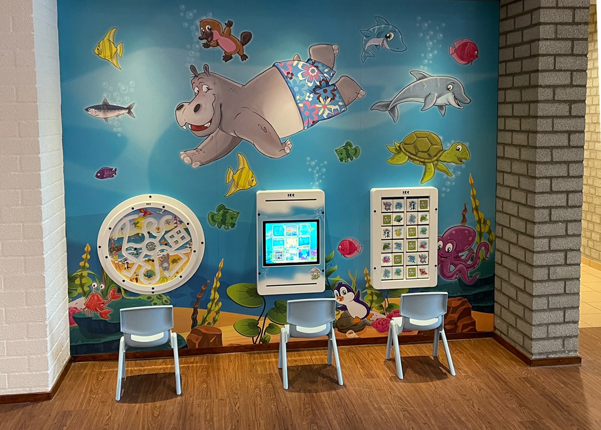 Foto van de gerealiseerde Jip-speelmuur met stoeltjes en touchscreen